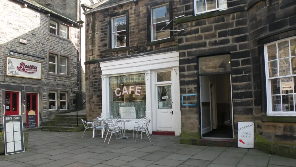 Façade d'un café convivial avec des tables en terrasse sur une rue pavée.