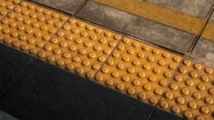 Dalles podotactiles jaunes au sol pour guider les personnes malvoyantes sur un quai.