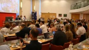 Vue d'une assemblée politique réunie dans une grande salle de conférence avec des élus.