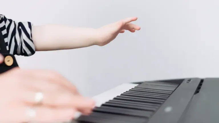 Gros plan sur les mains d'un enfant jouant du piano sur fond blanc.