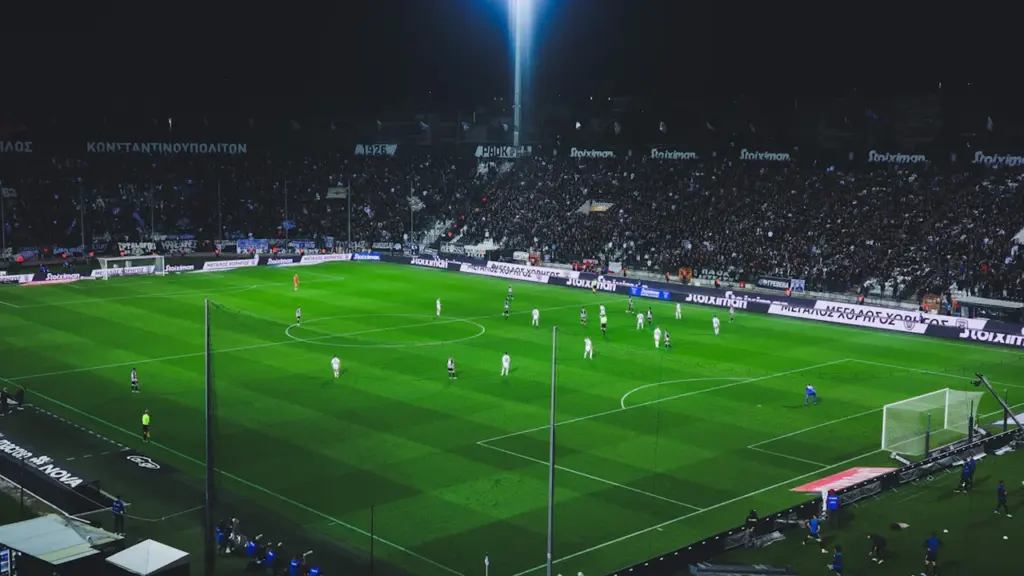 Vue nocturne d'un terrain de football professionnel sous projecteurs puissants.