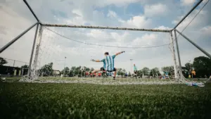 Un joueur de football effectue un arrêt devant les cages sur un terrain extérieur.