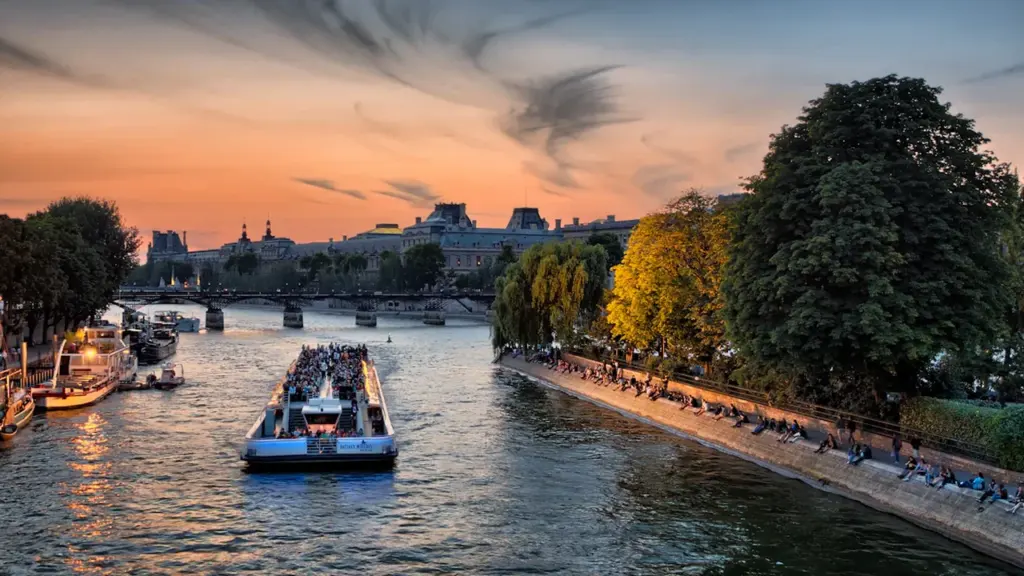 Vue panoramique de la Seine et des quais parisiens au coucher du soleil.