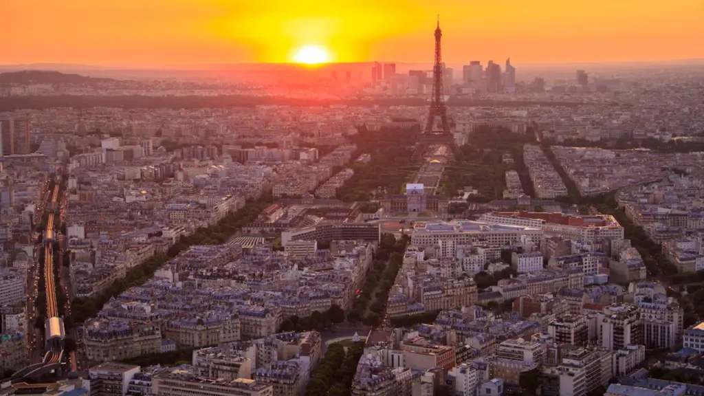Vue aérienne panoramique de Paris avec la tour Eiffel sous un coucher de soleil doré.