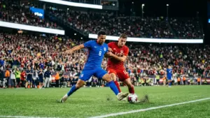 Un joueur de football américain en bleu lutte contre un joueur canadien en rouge.