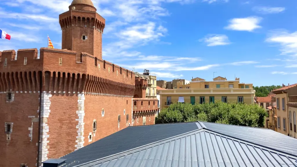 Vue panoramique sur les toits et le Castillet emblématique de Perpignan en été.