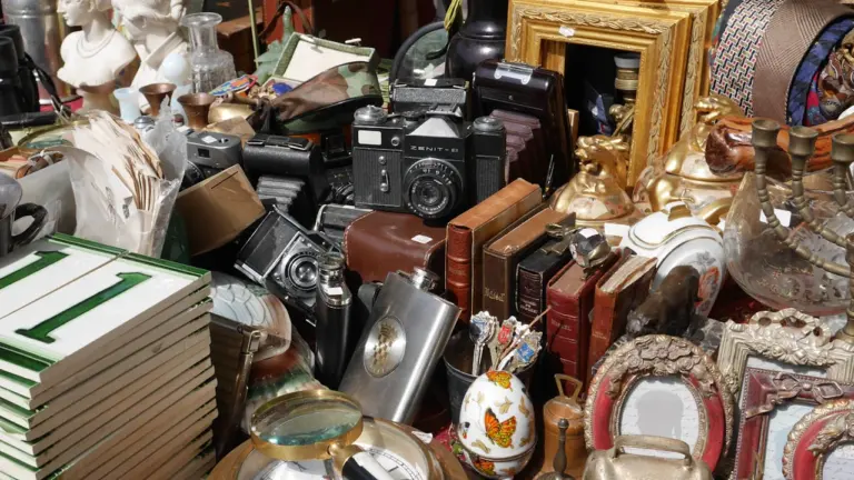Objets anciens et appareils photo vintage exposés sur un stand de brocante en extérieur.