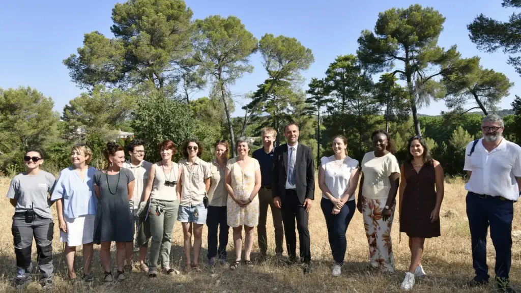 Un groupe diversifié de personnes pose pour une photo en extérieur sous un ciel ensoleillé.