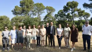 Un groupe diversifié de personnes pose pour une photo en extérieur sous un ciel ensoleillé.
