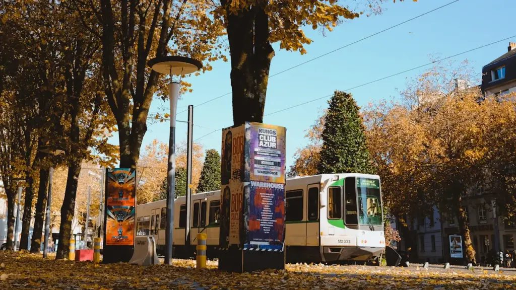 Un tramway circule dans une rue bordée d'arbres à Nantes en automne.