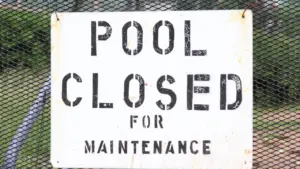 Panneau blanc indiquant la fermeture de la piscine pour travaux de maintenance.