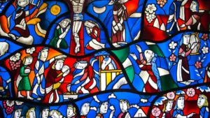 Détail coloré d'un vitrail représentant des scènes bibliques lumineuses et détaillées.