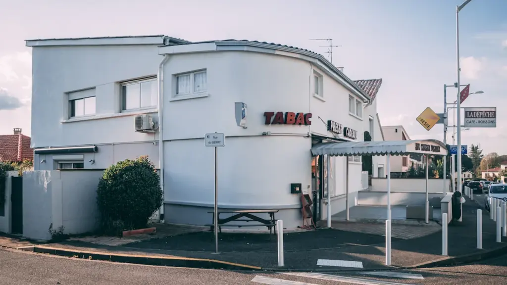 Façade d'un bâtiment blanc moderne situé dans un quartier urbain français ensoleillé.