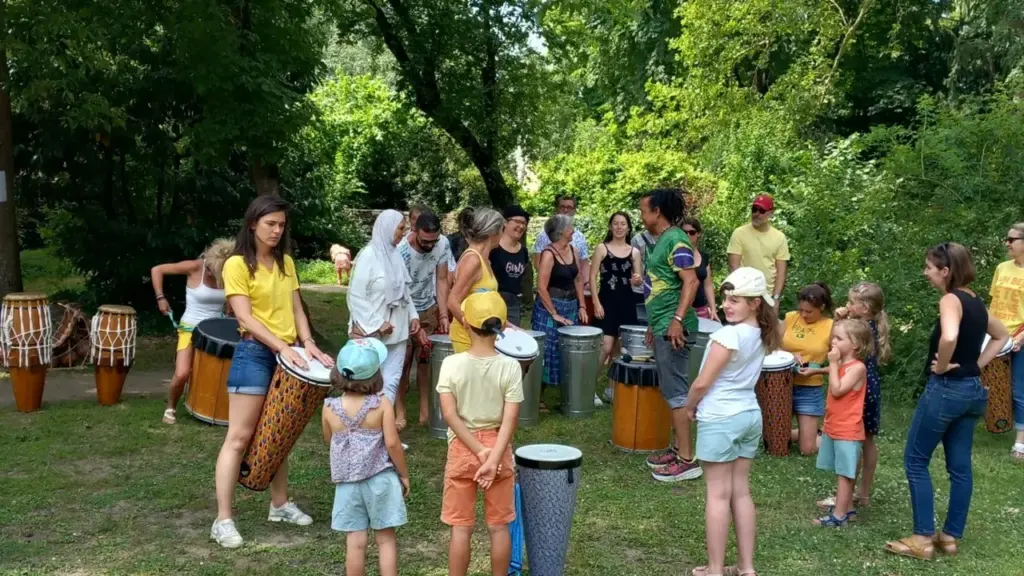 Un groupe diversifié de personnes participe à un atelier de percussions en plein air.