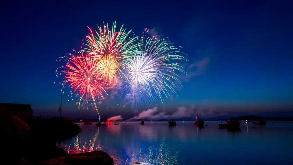 Magnifique feu d'artifice illuminant le ciel nocturne au-dessus d'un plan d'eau calme.