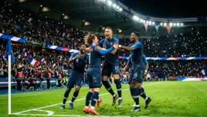 Des joueurs de l'équipe de France de football célèbrent joyeusement un but marqué sur le terrain.