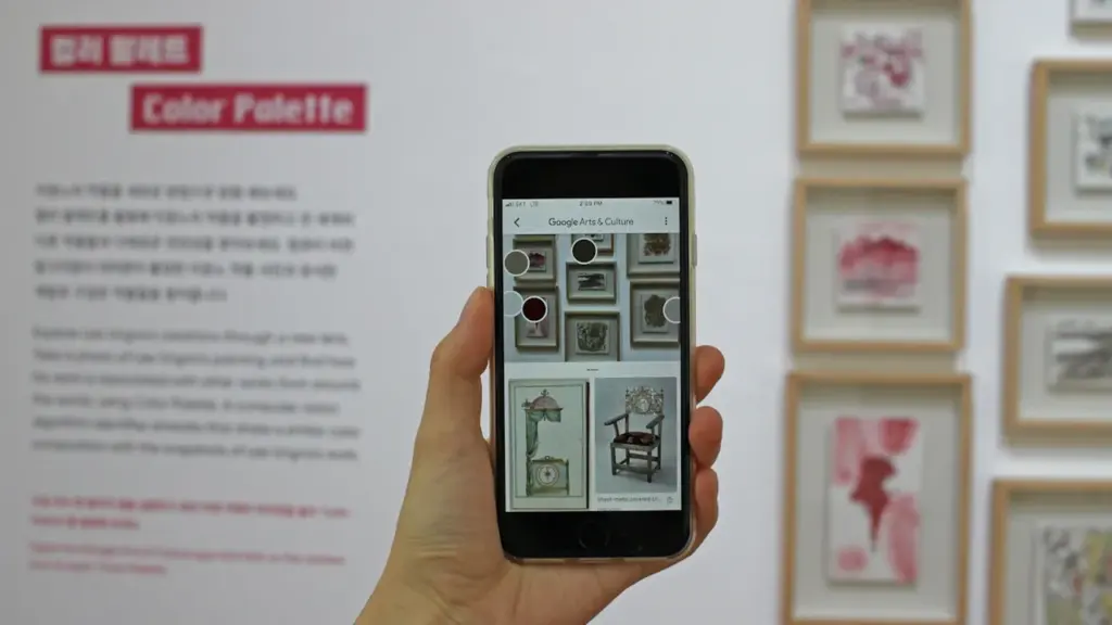 Main d'un visiteur utilisant son smartphone dans une exposition culturelle interactive moderne.