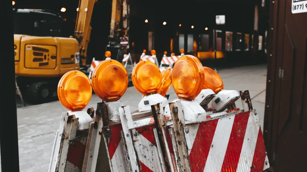 Barrières de chantier orange et blanches avec feux de signalisation sur une rue urbaine.
