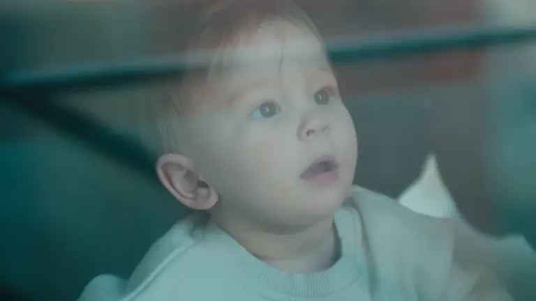 Un jeune enfant observe attentivement à travers la vitre d'une voiture.