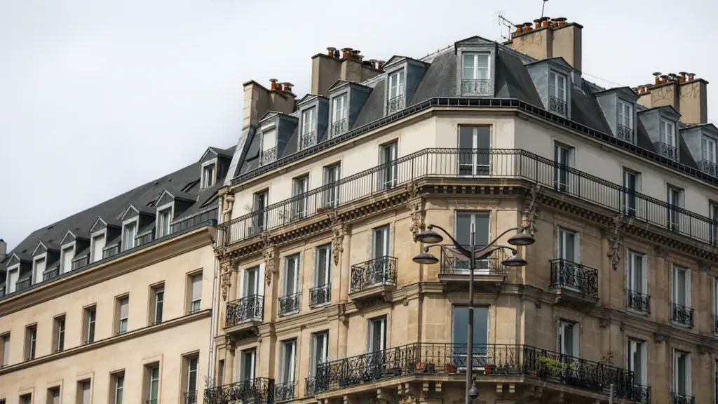 Façade classique d'un immeuble parisien avec toits en zinc sous un ciel nuageux.