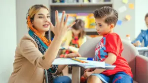 Une enseignante montre des chiffres avec ses doigts à un jeune élève attentif.