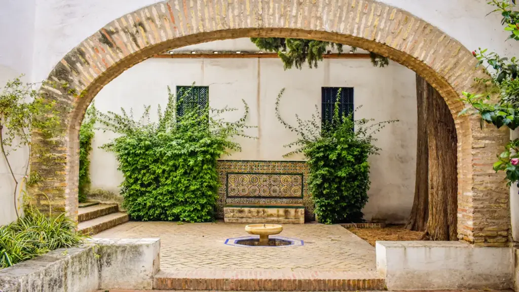 Une cour intérieure pittoresque avec une arche en pierre et des plantes en pots.