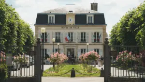Façade classique d'un hôtel de ville français avec des drapeaux flottant au vent.