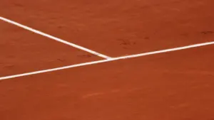Gros plan sur les lignes blanches d'un court de tennis en terre battue.