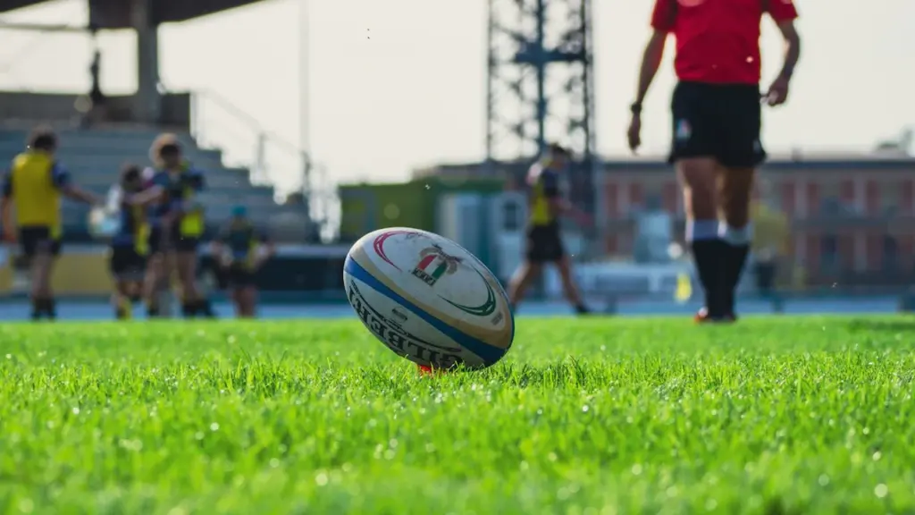 Ballon de rugby posé sur une pelouse verte dans un stade.