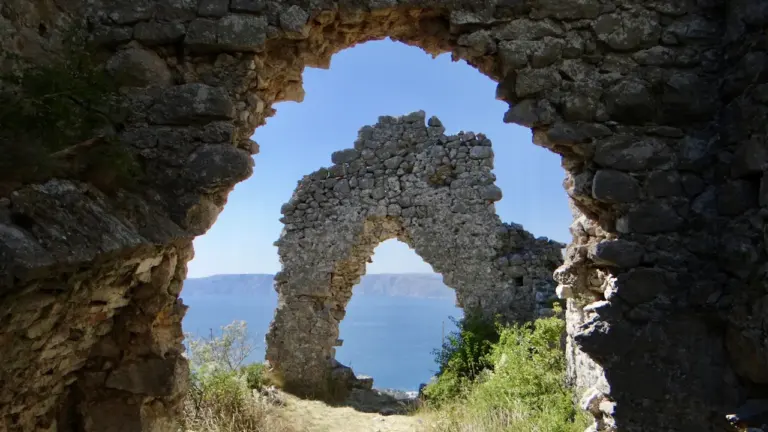 Une arche en pierre antique offrant une vue panoramique sur la mer Méditerranée.