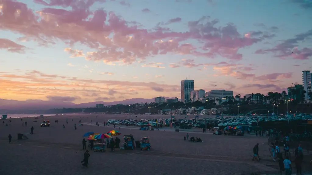 Coucher de soleil coloré sur une plage urbaine animée avec des bâtiments en arrière-plan.